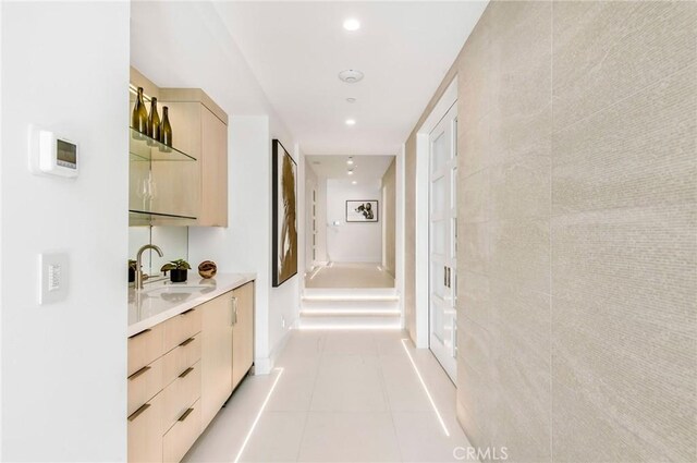 hallway with tile walls, light tile patterned floors, and sink