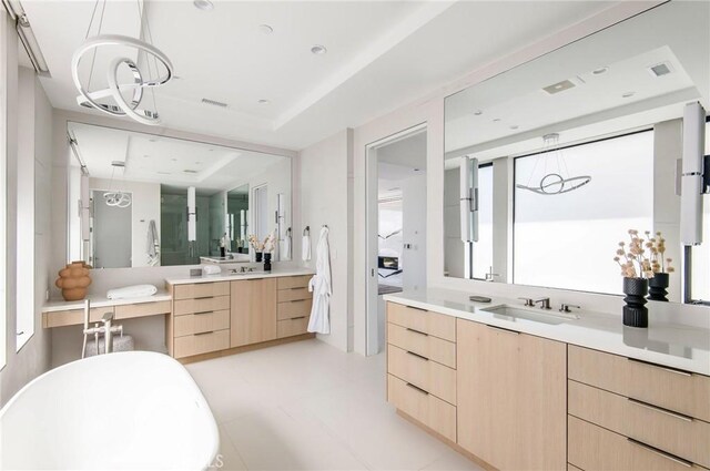 bathroom with a bathing tub, vanity, an inviting chandelier, and a raised ceiling