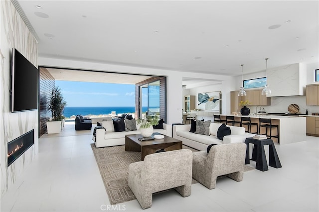 living room featuring a water view, sink, a high end fireplace, and a wealth of natural light