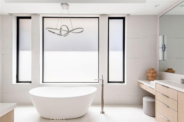 bathroom featuring vanity, tile patterned floors, and a tub