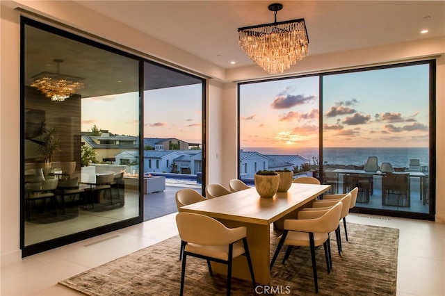 dining area featuring an inviting chandelier, a water view, and tile patterned floors