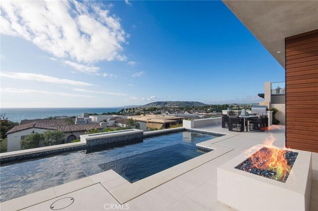 view of pool featuring a fire pit, a water view, and a patio area