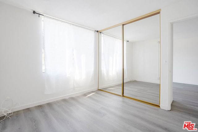 unfurnished bedroom featuring a closet, light hardwood / wood-style floors, and multiple windows