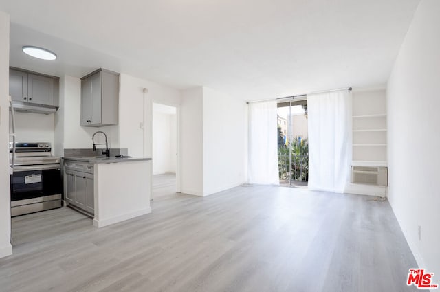 kitchen with light hardwood / wood-style floors, sink, gray cabinetry, a wall mounted air conditioner, and stainless steel range with electric stovetop