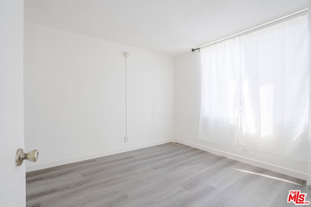 spare room featuring light hardwood / wood-style flooring and a healthy amount of sunlight