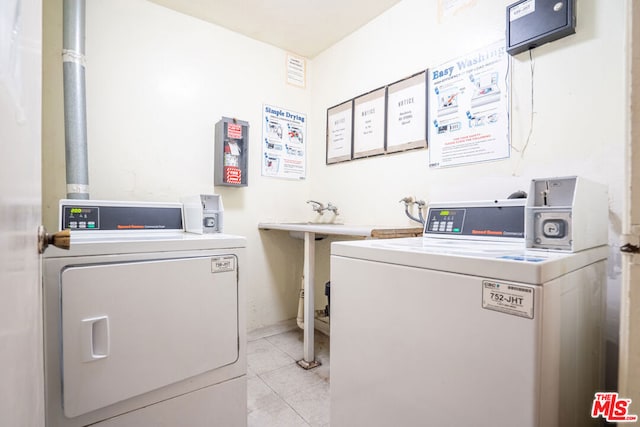 clothes washing area featuring light tile patterned floors and washer and clothes dryer