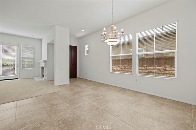 carpeted empty room featuring a wealth of natural light and an inviting chandelier