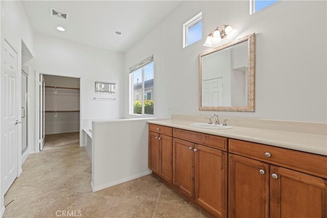 bathroom with a tub to relax in, vanity, and a healthy amount of sunlight