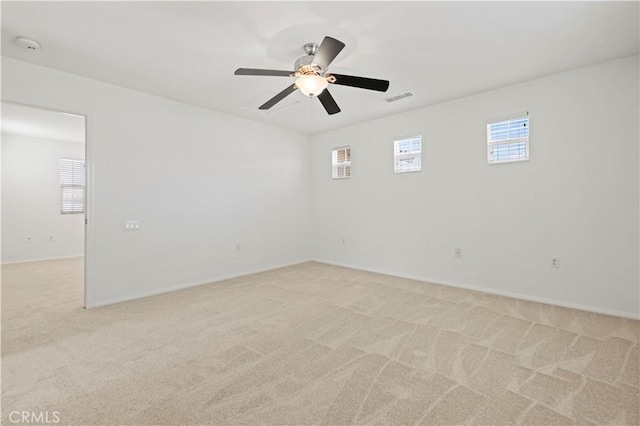 empty room with ceiling fan, light colored carpet, and a wealth of natural light