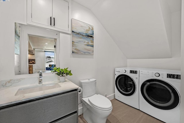 bathroom with vanity, toilet, independent washer and dryer, tile patterned floors, and vaulted ceiling