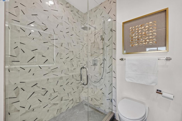 bathroom featuring a shower with shower door and toilet