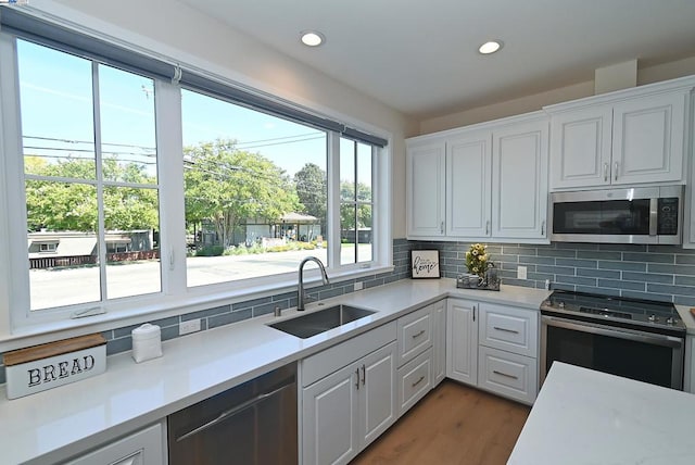 kitchen featuring decorative backsplash, white cabinetry, appliances with stainless steel finishes, and sink