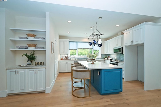 kitchen with blue cabinets, appliances with stainless steel finishes, light hardwood / wood-style floors, and a kitchen island