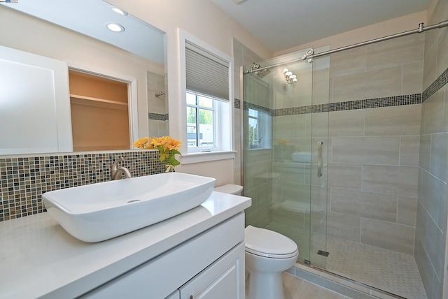 bathroom featuring tile patterned flooring, a shower with door, vanity, and toilet