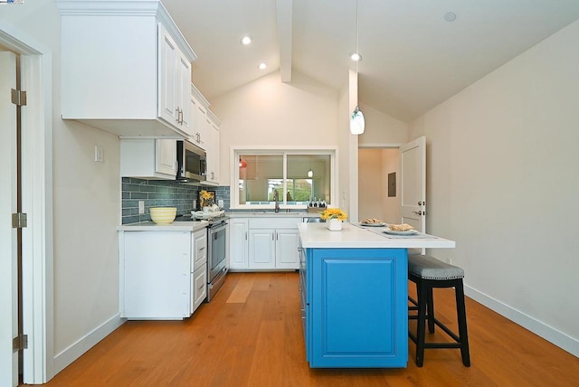 kitchen with appliances with stainless steel finishes, white cabinetry, pendant lighting, light wood-type flooring, and vaulted ceiling with beams