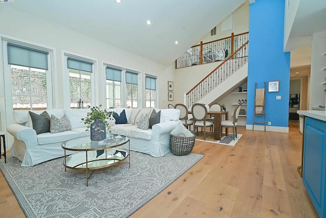 living room with high vaulted ceiling and light wood-type flooring