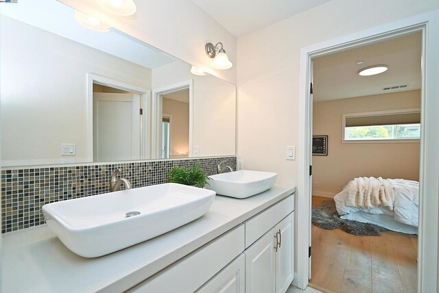 bathroom with backsplash, vanity, and hardwood / wood-style floors