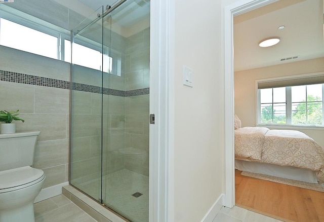 bathroom featuring toilet, tile patterned floors, and an enclosed shower