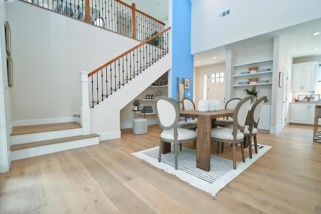 dining space featuring a high ceiling, light hardwood / wood-style floors, and built in features