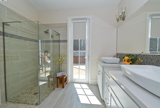 bathroom with a notable chandelier, vanity, backsplash, and a tile shower