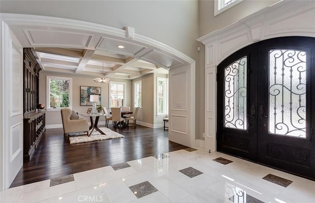 entrance foyer featuring french doors, beamed ceiling, coffered ceiling, and hardwood / wood-style flooring