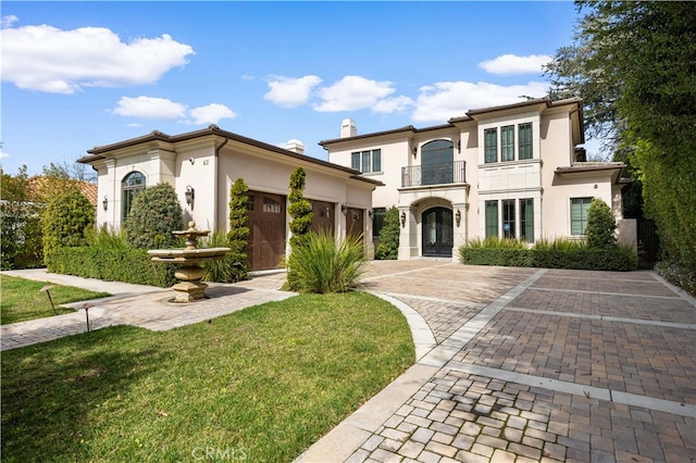 mediterranean / spanish home with a garage, decorative driveway, a front yard, and stucco siding