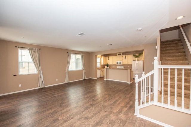 unfurnished living room with a healthy amount of sunlight and dark hardwood / wood-style flooring