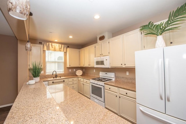 kitchen with cream cabinets, hanging light fixtures, light stone counters, sink, and white appliances