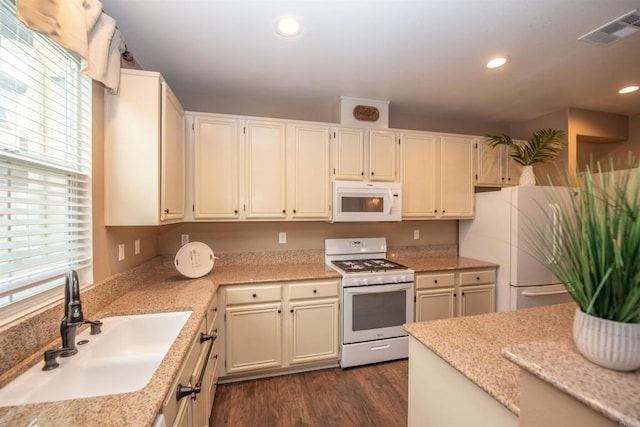 kitchen featuring white appliances, light stone countertops, dark wood-type flooring, and sink