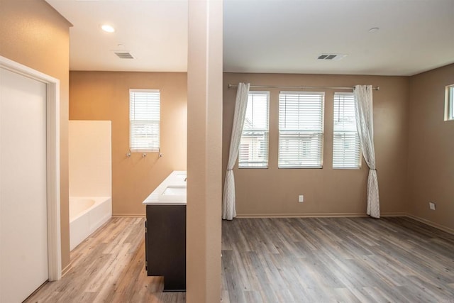 bathroom with vanity, a tub, a wealth of natural light, and hardwood / wood-style floors