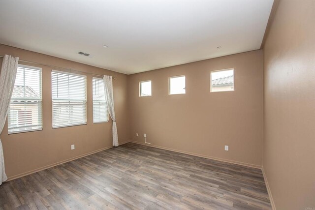 unfurnished room featuring dark wood-type flooring and plenty of natural light