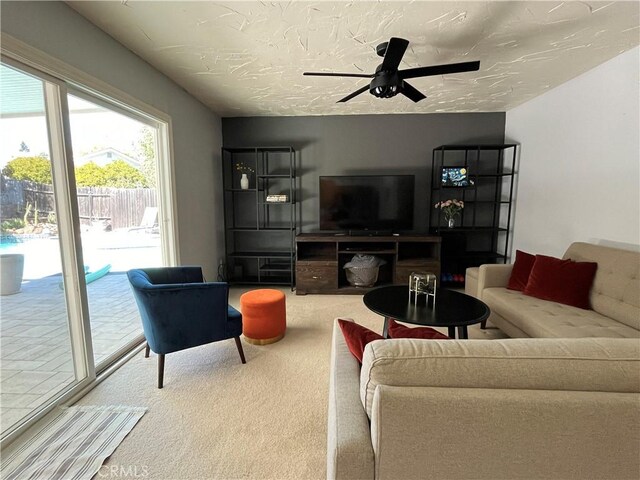 carpeted living room with a textured ceiling and ceiling fan