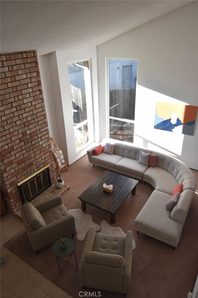 living room featuring a brick fireplace and a textured ceiling