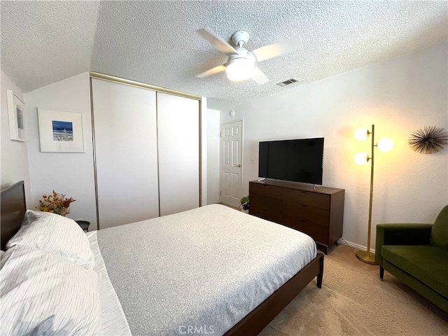 carpeted bedroom with a closet, vaulted ceiling, ceiling fan, and a textured ceiling