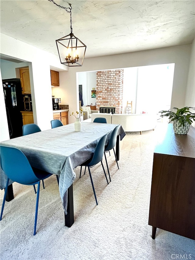 carpeted dining space with an inviting chandelier and a fireplace