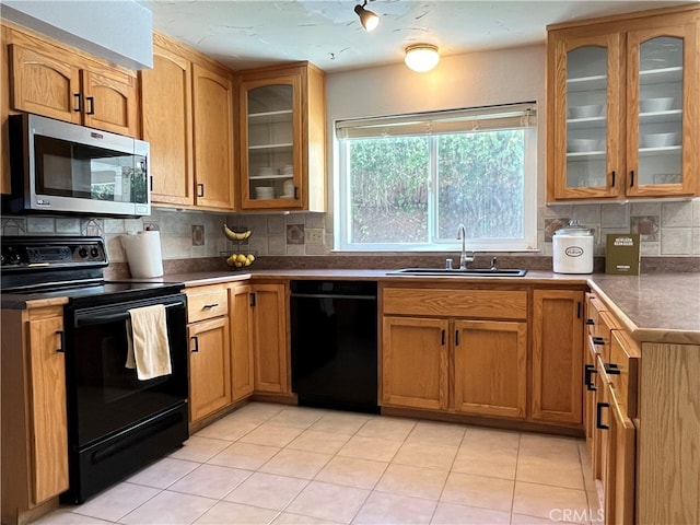 kitchen with backsplash, black appliances, light tile patterned floors, and sink