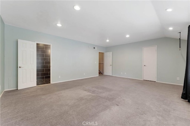 carpeted spare room featuring vaulted ceiling