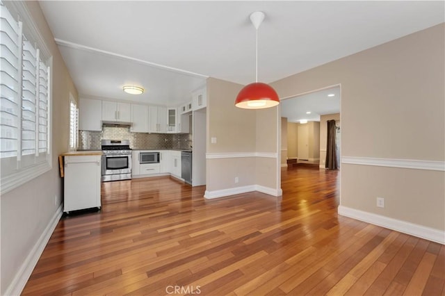 kitchen with white cabinetry, light hardwood / wood-style flooring, hanging light fixtures, and appliances with stainless steel finishes