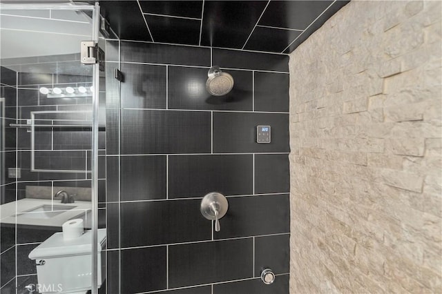 bathroom with a tile shower, toilet, and tile walls