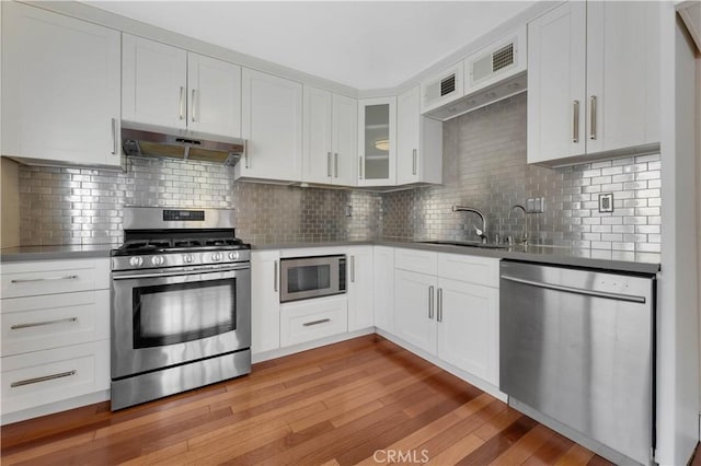 kitchen featuring light hardwood / wood-style flooring, white cabinets, extractor fan, and appliances with stainless steel finishes