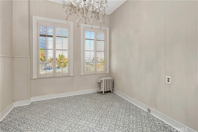 spare room featuring radiator and an inviting chandelier