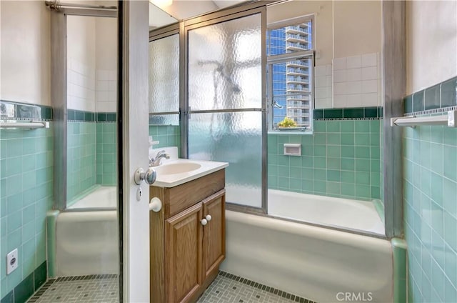 bathroom with shower / bath combination with glass door, vanity, tile patterned flooring, and tile walls