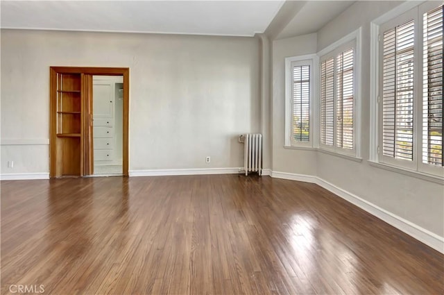 empty room with radiator heating unit and dark wood-type flooring