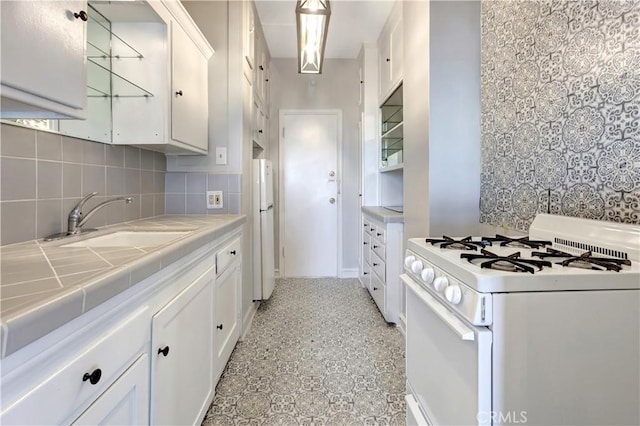 kitchen with white cabinets, white appliances, tile counters, and sink