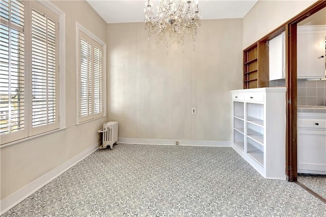 unfurnished room with radiator heating unit and a chandelier