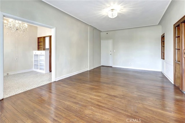 empty room featuring hardwood / wood-style floors and a notable chandelier