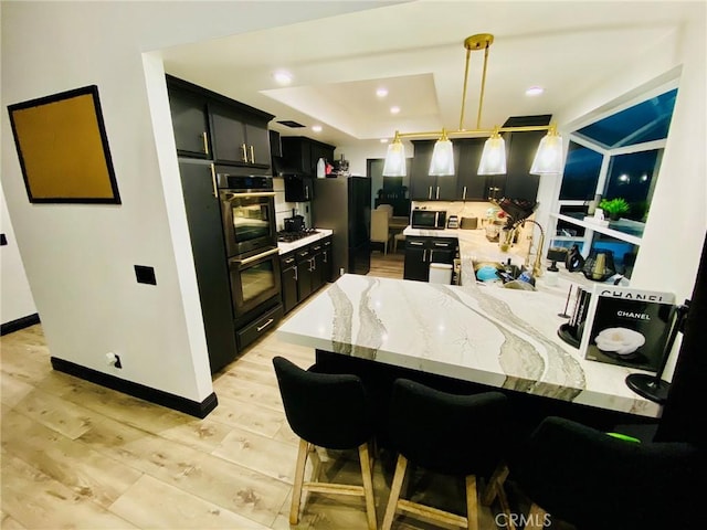 kitchen with kitchen peninsula, a kitchen breakfast bar, refrigerator, decorative light fixtures, and light hardwood / wood-style floors