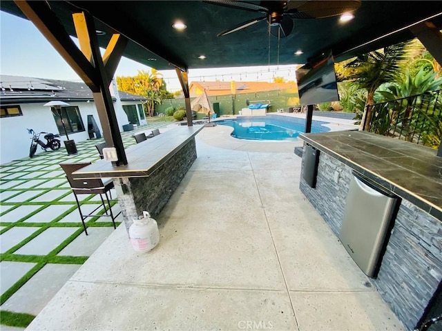 view of swimming pool with ceiling fan, exterior bar, and a patio