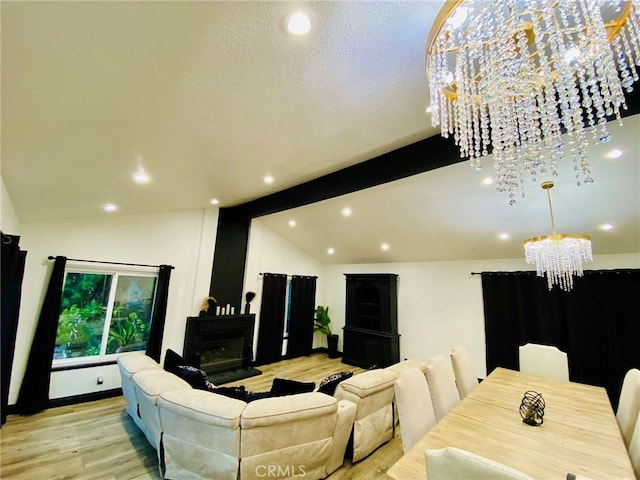 living room featuring a notable chandelier, lofted ceiling with beams, light wood-type flooring, and a fireplace