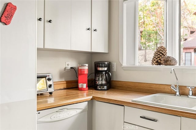 kitchen with dishwasher, white cabinetry, and sink